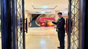 A hotel lobby with a staircase, a reception desk, and a person standing near the entrance. - Fengleyuan Hotel (Zhengzhou)