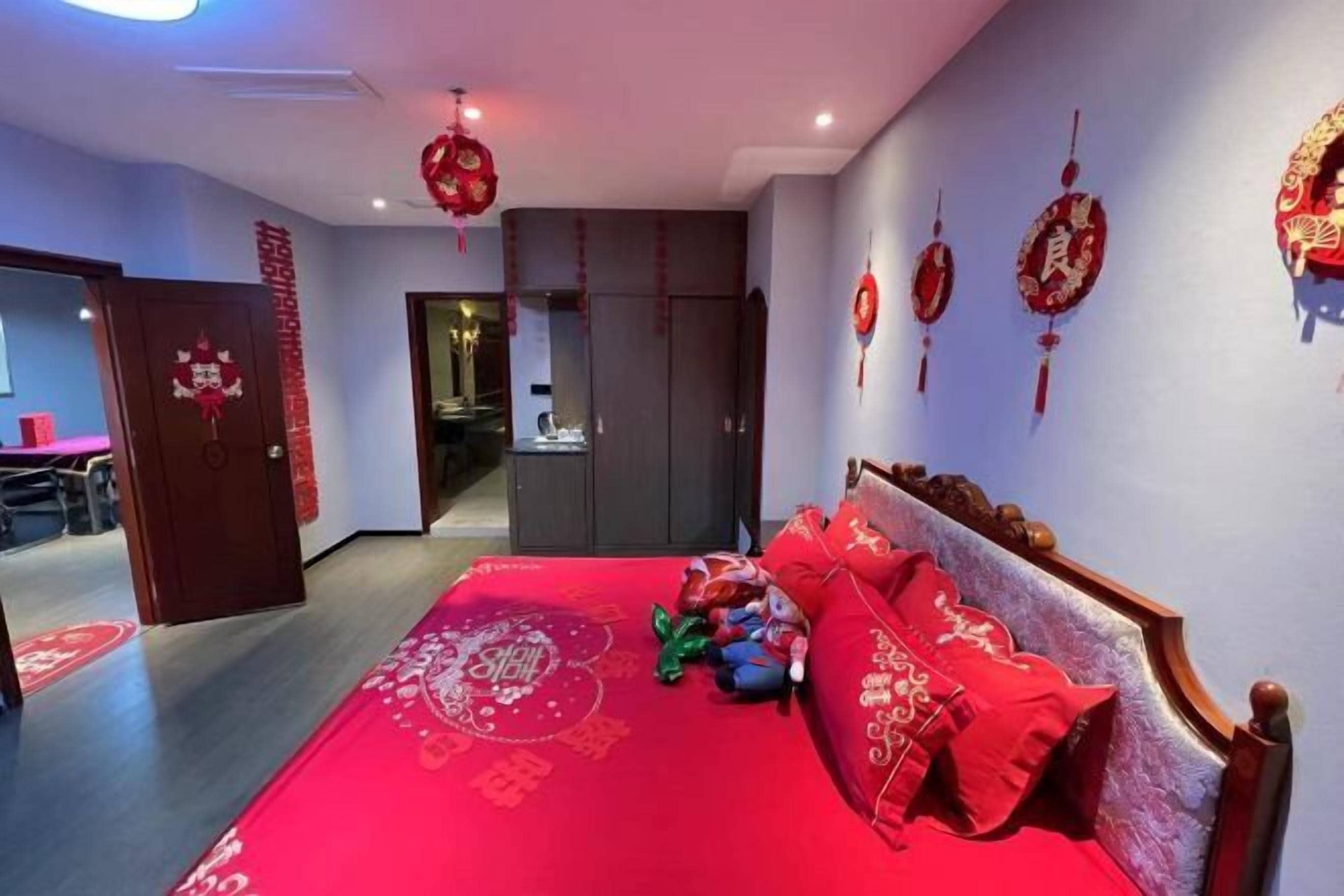 A bedroom with a red bedspread, wooden headboard, and red pillows.