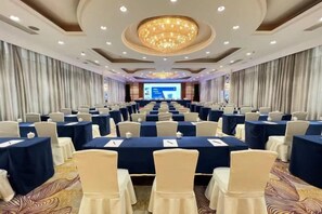 A conference room with rows of tables and chairs, a large screen at the front, and a chandelier. - Fengleyuan Hotel (Zhengzhou)