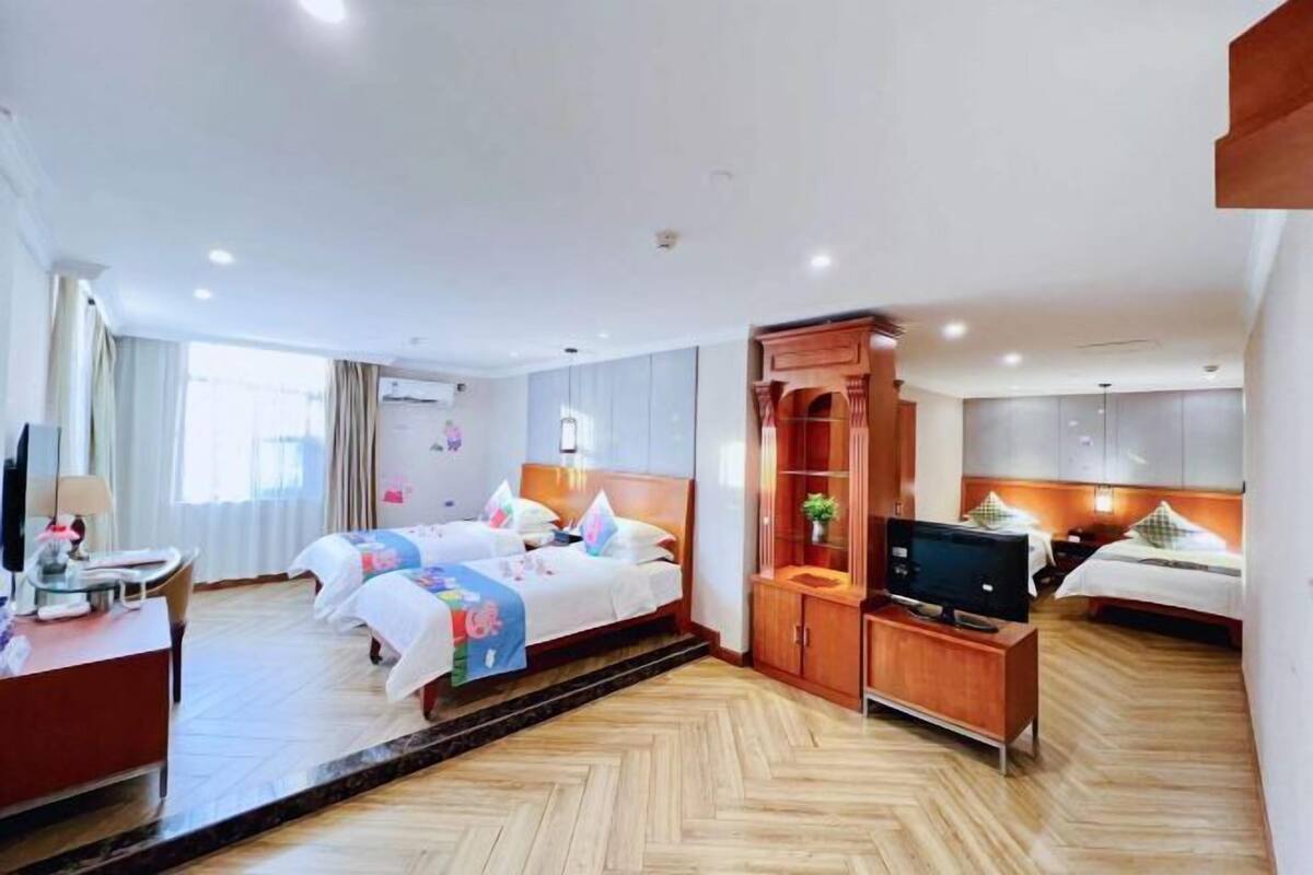 A hotel room with two beds, a TV, a desk, and a wardrobe.