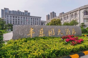 A stone sign with Chinese characters, surrounded by greenery and a paved area. - Fengleyuan Hotel (Zhengzhou)