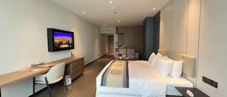 Une chambre d’hôtel moderne équipée d’un lit, d’un bureau, d’une chaise et d’un téléviseur.
