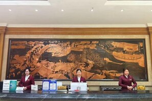 A reception desk with a large mural in the background. - Fengleyuan Hotel (Zhengzhou)