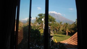 A view of a mountain with a clear sky, surrounded by greenery and a few buildings. - Blue Royal Amed (Karangasem)