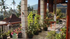 A covered outdoor area with potted plants and a wooden table. - Blue Royal Amed (Karangasem)