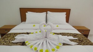 A neatly made bed with white linens and a swan-shaped towel arrangement. - Blue Royal Amed (Karangasem)