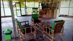A covered outdoor seating area with wooden furniture and a bar counter.
