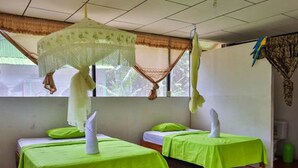 A room with two beds, each covered with a green bedspread and white pillows.
