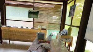 A buffet table with various dishes, including a watermelon dish, in a room with wooden walls and a window.