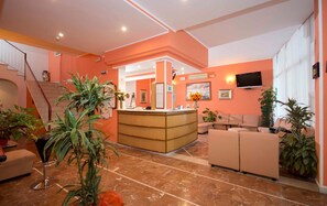 A hotel lobby with a reception desk, seating area, and a staircase. - Hotel veliero (Rimini)
