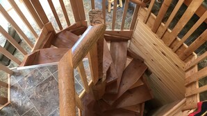 Una escalera de caracol hecha de tablones de madera con barandilla de metal, que conduce a un piso superior.