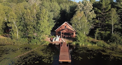 Maalaismainen mökki järvellä lähellä kuvassa olevia kiviä, kalastus, saari, kanootti, veneet