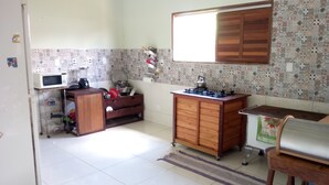 A compact kitchen with a microwave, stove, and wooden cabinets. - Ximenes and Daubian House (Bonito)