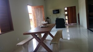 A spacious room with a wooden dining table, benches, and a television mounted on the wall. - Ximenes and Daubian House (Bonito)