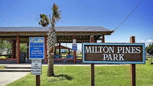 Un panneau indiquant le parc Milton Pines, avec une affiche indiquant les heures de fermeture et interdisant le skateboard.