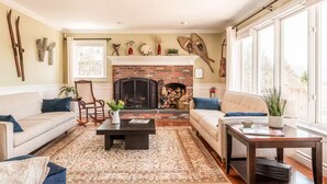 A living room with a fireplace, two sofas, a coffee table, and a large window.