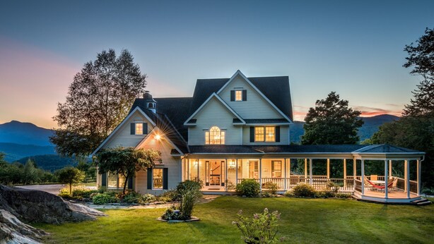 A two-story house with a large porch and a covered outdoor seating area.