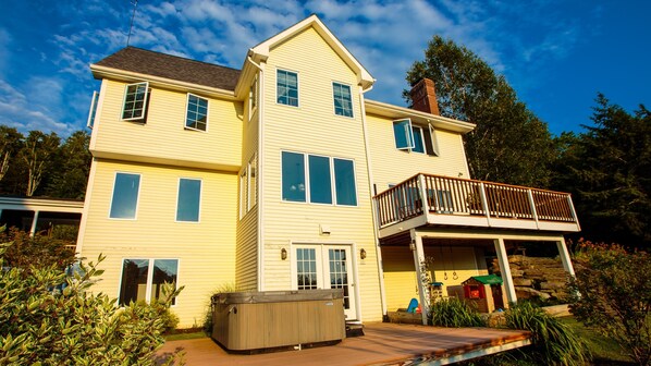 A two-story house with a balcony, a hot tub, and a covered porch.