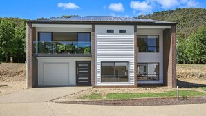 A modern two-story house with a garage, large windows, and solar panels on the roof. - BrightAway - Located in Bright, Victoria (BRIGHT)