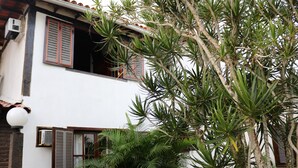 A white building with brown shutters and a balcony. - BOAT HOUSE - Charm and Comfort on Geribá Beach (Búzios)