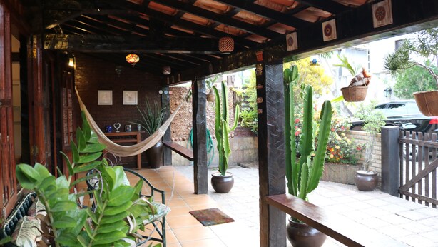 A covered outdoor area with a hammock, potted plants, and a wooden bench. - BOAT HOUSE - Charm and Comfort on Geribá Beach (Búzios)