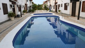 A swimming pool with a tiled edge and a small seating area with chairs. - BOAT HOUSE - Charm and Comfort on Geribá Beach (Búzios)