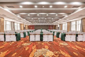 A conference room with rows of tables, chairs, and a carpeted floor. - Hua Tian Hotel (Tianshui)