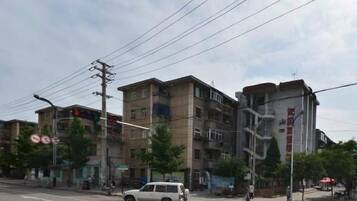 Un edificio de varios pisos con una escalera, un paso de peatones y un vehículo blanco.