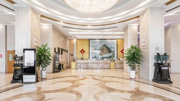 A spacious lobby with a grand chandelier, reception desk, and potted plants. - Hua Tian Hotel (Tianshui)