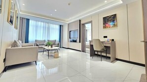 A modern living room with a sofa, coffee table, and a TV. - Hua Tian Hotel (Tianshui)