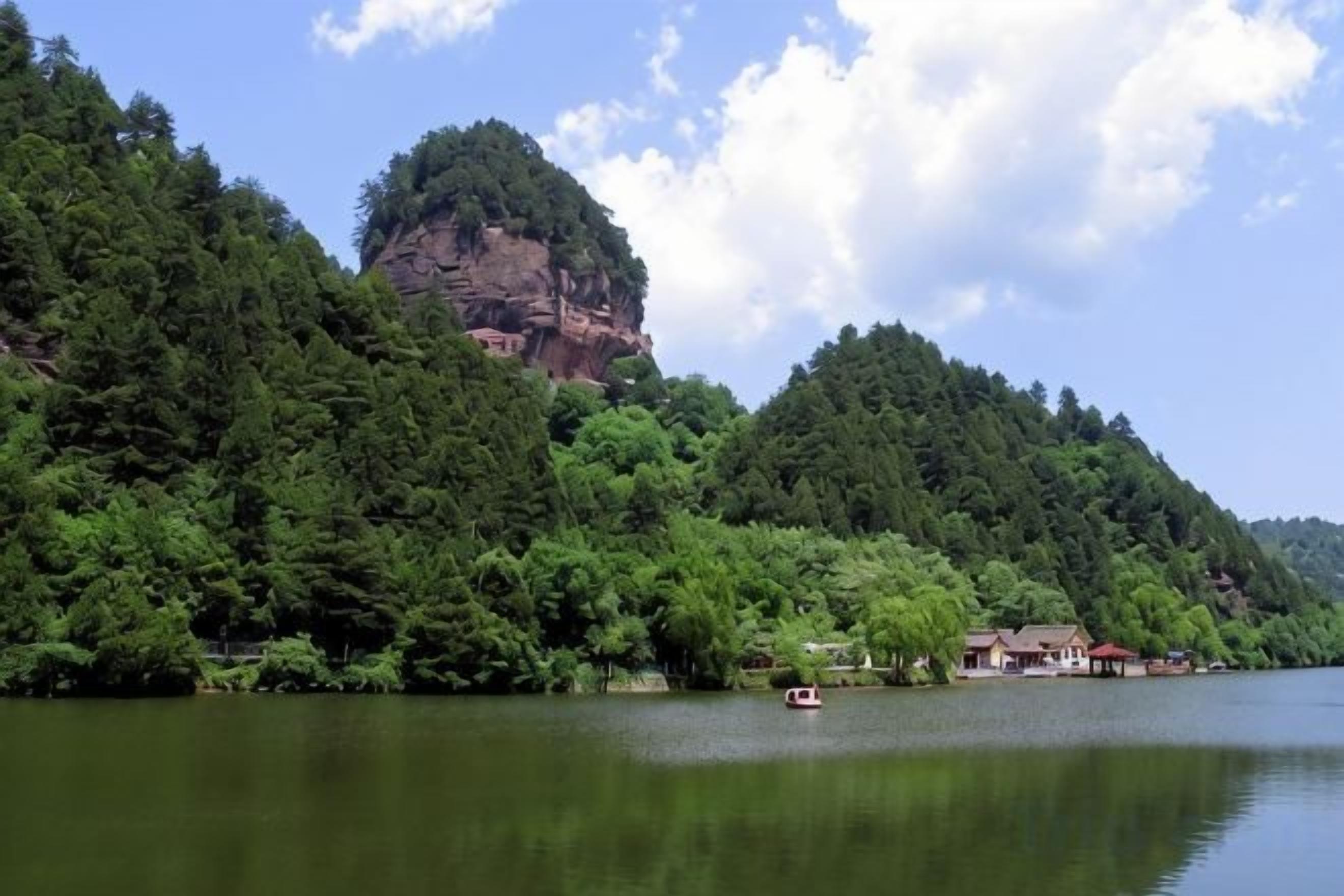 A lake with a forested hill and a small boat.