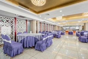 A banquet hall with round tables, purple-covered chairs, and decorative wall panels. - Hua Tian Hotel (Tianshui)