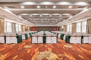 A conference room with rows of tables, green tablecloths, and white chairs. - Hua Tian Hotel (Tianshui)