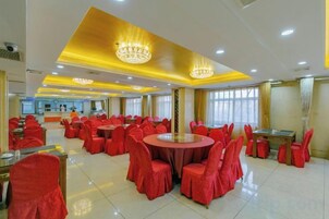 Un salón de banquetes con mesas redondas y sillas, una zona de recepción y candelabros.