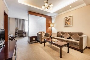 Una sala de estar moderna con un sofá, sillones, una mesa de centro y un televisor.