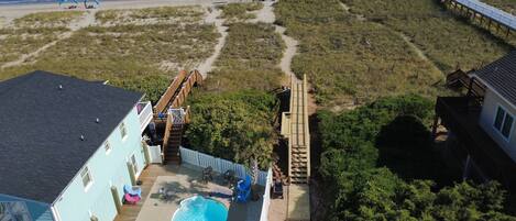 Una propiedad frente a la playa con piscina, terraza de madera y un sendero que lleva al océano.