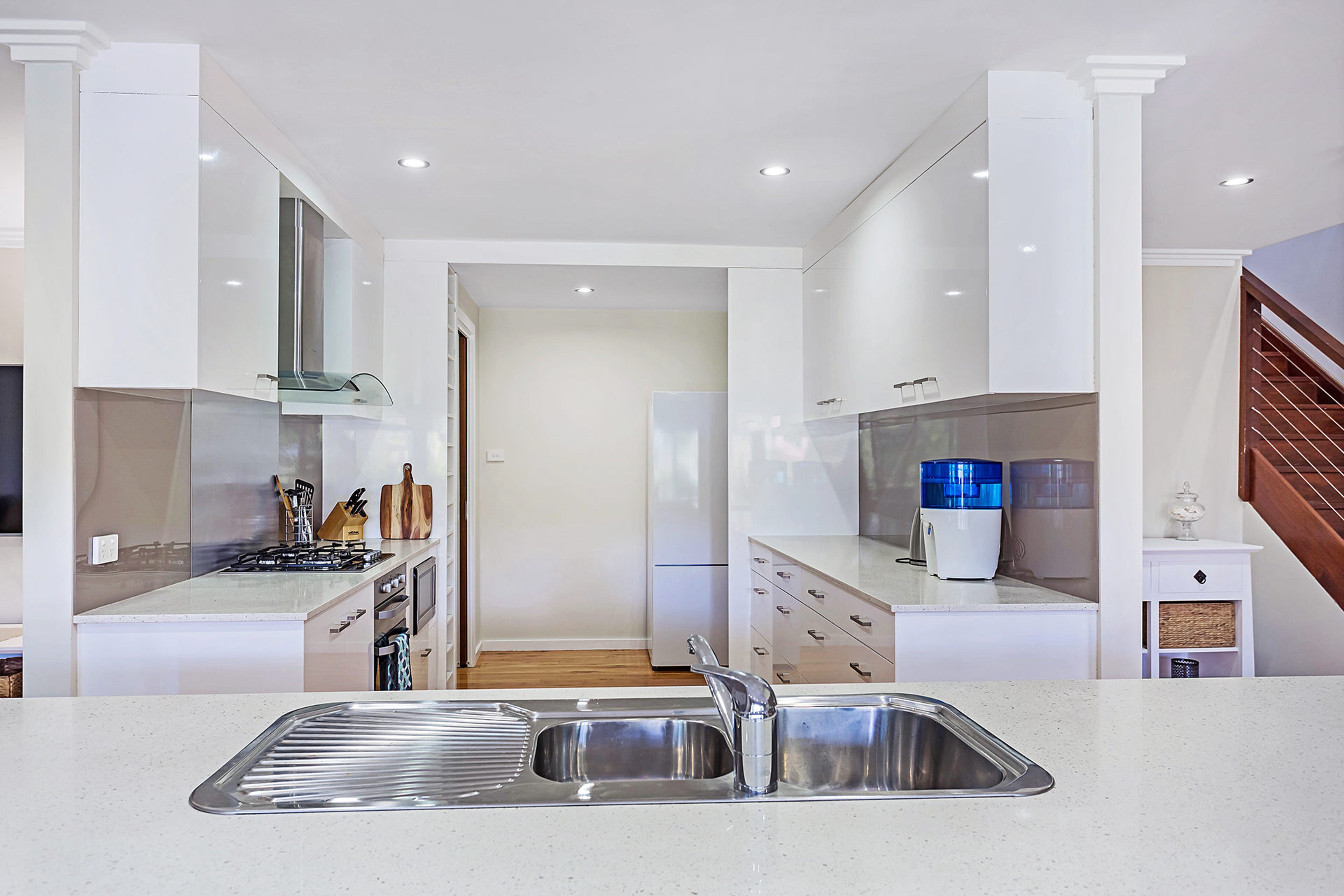 Una cocina moderna con un lavamanos de acero inoxidable, armarios blancos y una estufa visible.