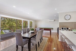 Een moderne keuken met een pooltafel, een eethoek met stoelen en een bar met krukken.