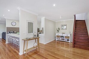 A modern interior with a kitchen, dining area, and a staircase. - Stellas at the Bay Coastal Home (Nelson Bay)