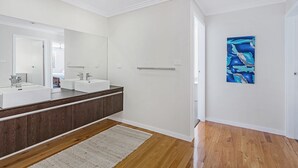 Ein Badezimmer mit einem Doppelwaschtisch, einem großen Spiegel und Holzboden.