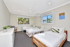 A hotel room with two beds, a desk, a chair, a ceiling fan, and large windows with views of trees. - Stellas at the Bay Coastal Home (Nelson Bay)