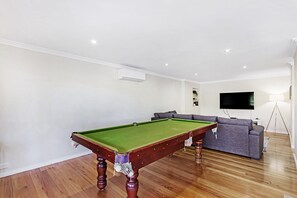 A pool table in a room with a sofa and a television.