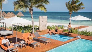 A poolside area with lounge chairs, umbrellas, and a view of the ocean. - LA AMADA CANCUN LUXURY CONDO 3 BR STEPS FROM BEACH MARINA (Isla Mujeres)
