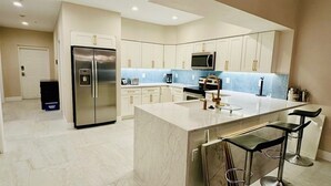 A modern kitchen with a central island, stainless steel appliances, and bar stools. - FABULOUS SPRING SALE! 🌸🌼at  Luxurious Waterfront  condo in Clearwater Beach  (Clearwater Beach)
