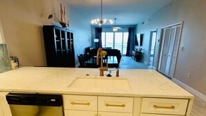 A kitchen with a large island, white cabinetry, and a dishwasher. - FABULOUS SPRING SALE! 🌸🌼at  Luxurious Waterfront  condo in Clearwater Beach  (Clearwater Beach)