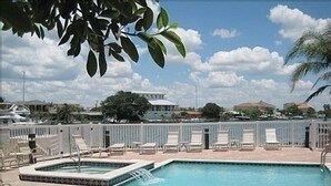 A rectangular pool with a small waterfall feature, surrounded by lounge chairs and a white fence. - FABULOUS SPRING SALE! 🌸🌼at  Luxurious Waterfront  condo in Clearwater Beach  (Clearwater Beach)
