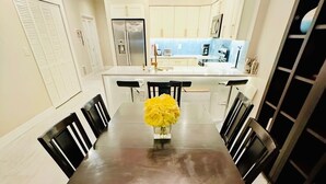A dining area with a long table, black chairs, and a vase of yellow flowers. - FABULOUS SPRING SALE! 🌸🌼at  Luxurious Waterfront  condo in Clearwater Beach  (Clearwater Beach)