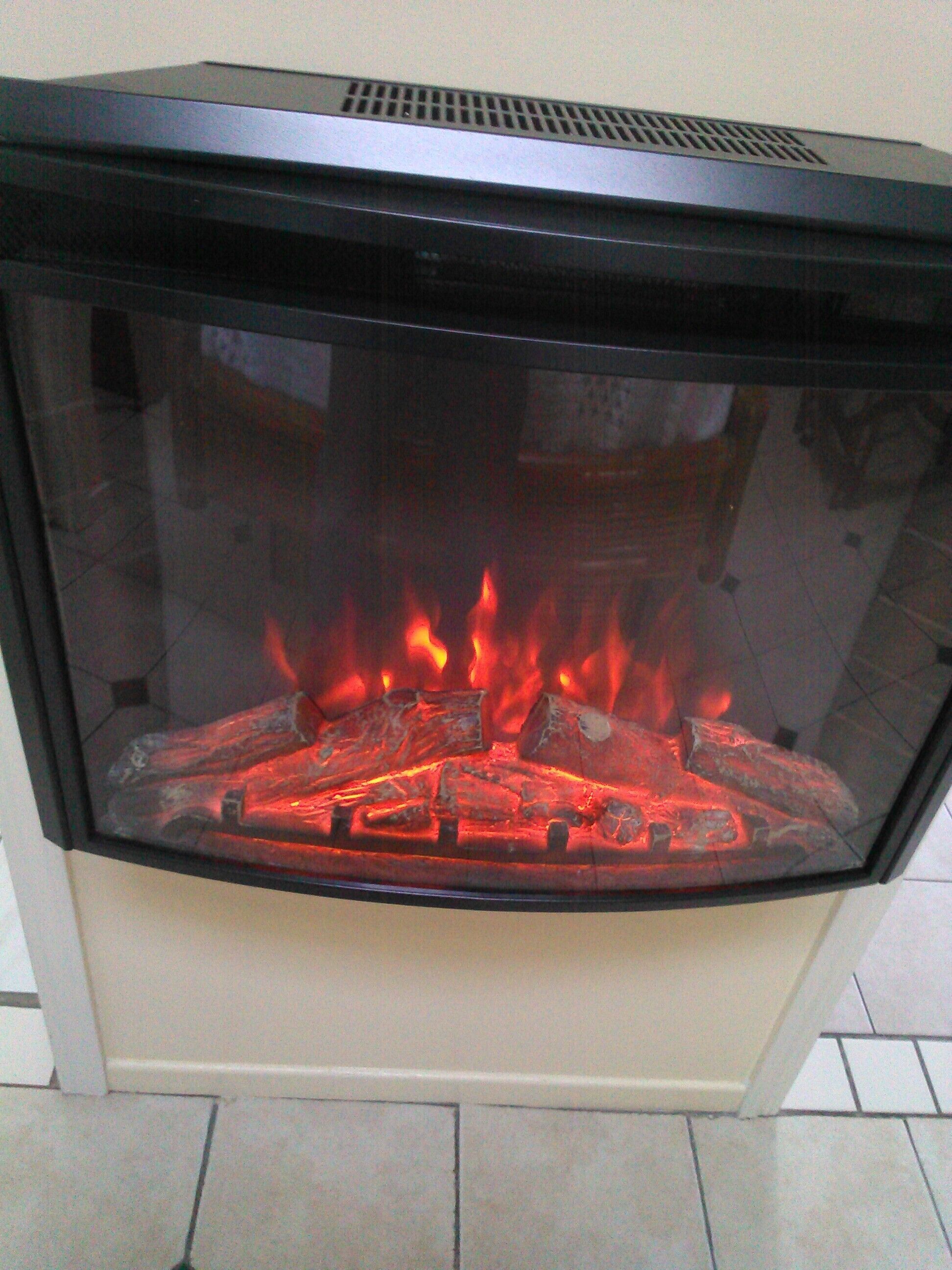 Chimenea con cerramiento de vidrio y leña ardiendo a la vista.