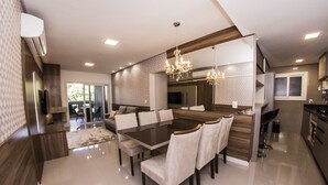 Un comedor moderno con una gran mesa rectangular, múltiples sillas y una araña.