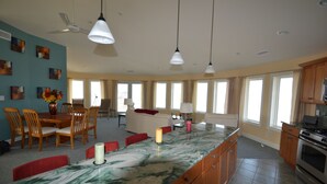 Una cocina amplia con una isla de mármol, armarios de madera y una zona de comedor con sillas y mesa.
